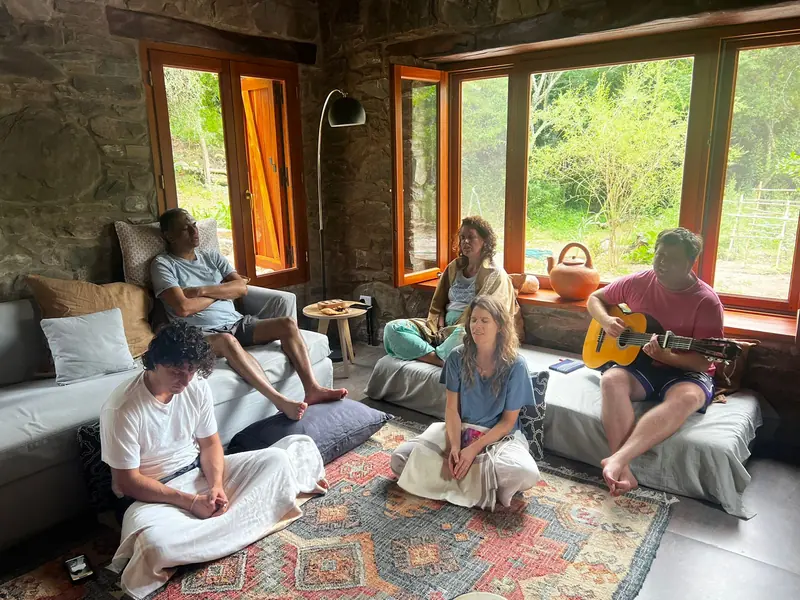 Amigos reunidos en el living de piedra de la casa de los fundadores, uno toca la guitarra
